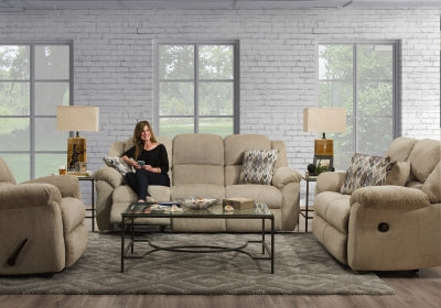 Woman sitting on a beige recliner in a living room with matching sofa and armchair.