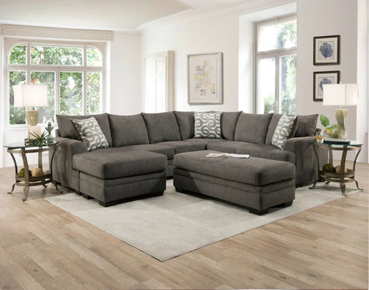 Gray sectional sofa in a living room with large windows and decorative items.